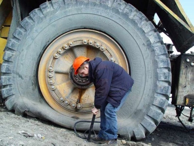 Мужик накачивает колесо БЕЛАЗА